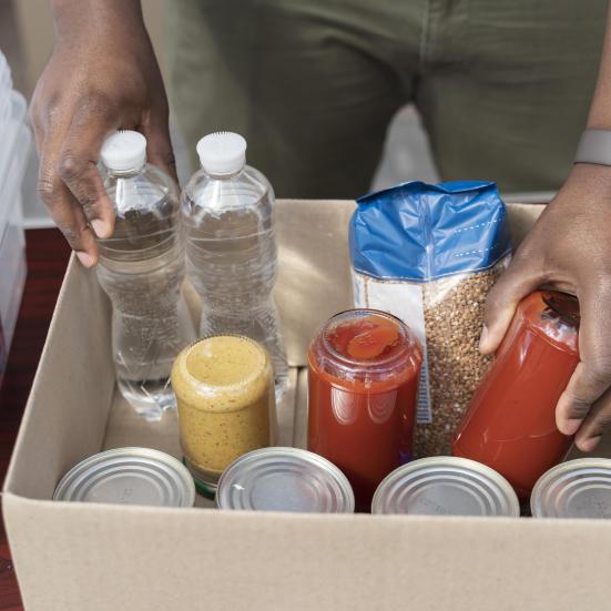 Billede fra Freepik: en man pakker mad og vandflaske ned i papkasse