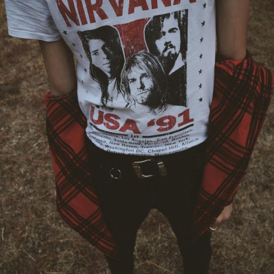 En person står i en hvid tshirt med banden "Nirvana" på