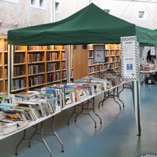 Bogsalg på Hovedbiblioteket, hvor man kan se et langbord fyldt med bøger og andre materialer til salg.