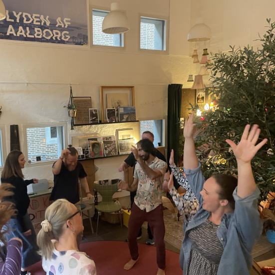 en gruppe mennesker danser i en rundkreds i Folkestuen på Hovedbiblioteket