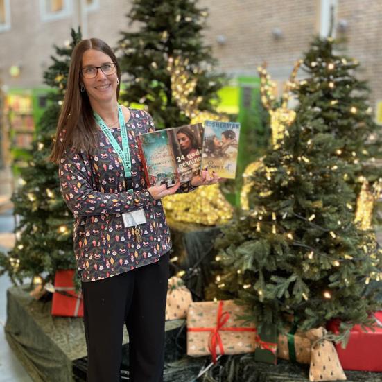 Line står foran juleudstilling på Hovedbiblioteket med tre af de omtalte bøger i hænderne.