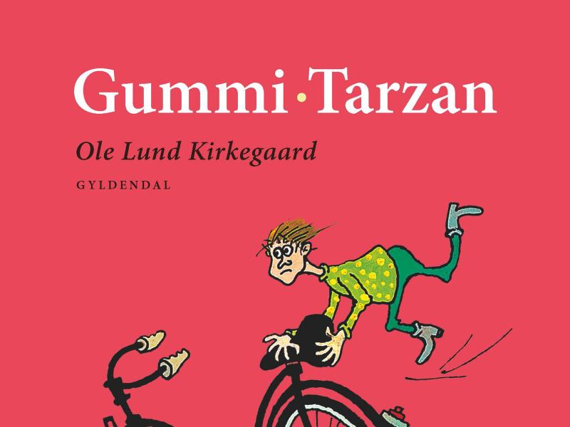 Forsiden til Ole Lund Kirkegaards bog "Gummi-Tarzan". En spinkel dreng hænger efter en stor cykel.