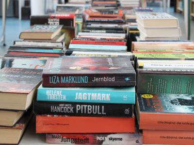 En masse bøger ligger udstillet på lange borde i et bibliotek.