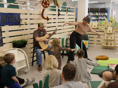 To bibliotekarer underholder med sang for en gruppe børn