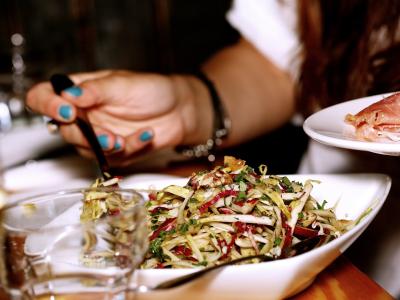 Billede af dyb tallerken med blandet salat. En hånd holder en gaffel ned i tallerkenen.