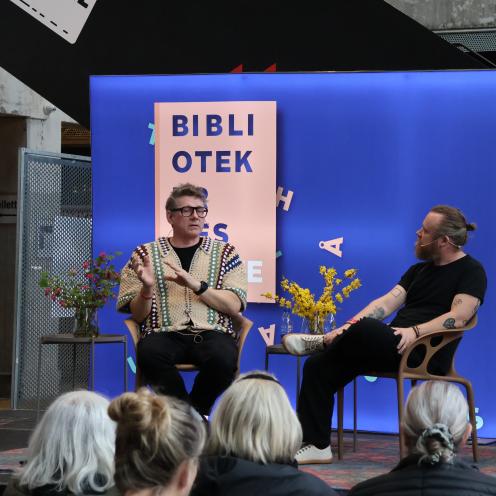To mennesker, Jørgen (tv) og Teis (tv) sidder på en scene og taler foran et publikum