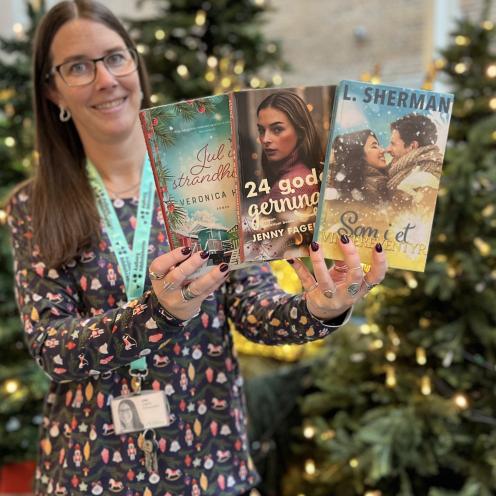 Line står foran juleudstilling på Hovedbiblioteket med tre af de omtalte bøger i hænderne.