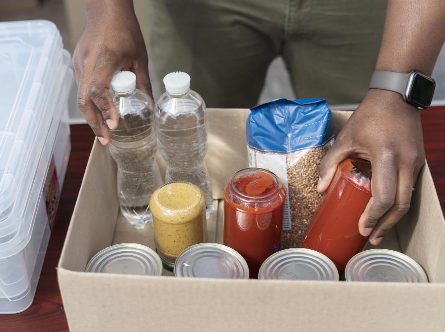 Billede fra Freepik: en man pakker mad og vandflaske ned i papkasse