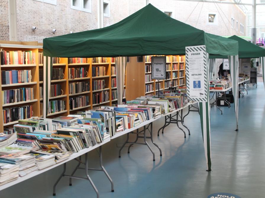 Bogsalg på Hovedbiblioteket, hvor man kan se et langbord fyldt med bøger og andre materialer til salg.